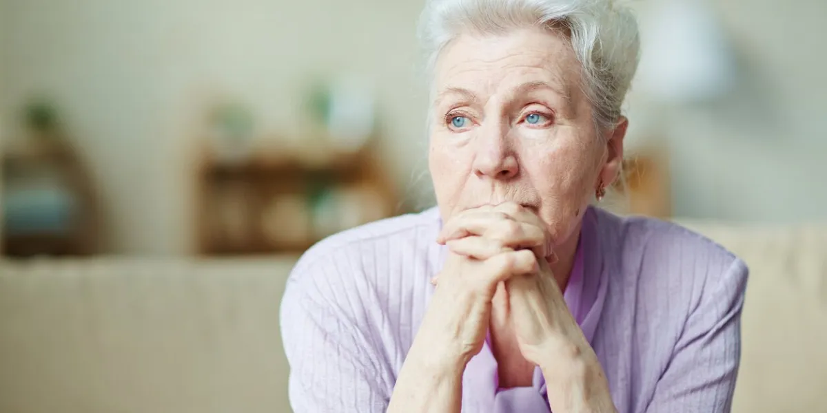 elderly woman keeping hands by her lips