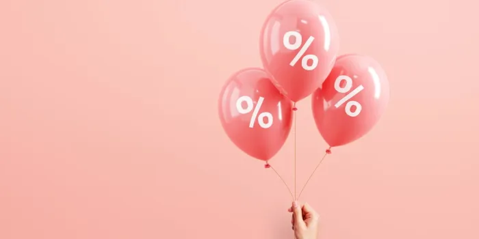 hand of woman holding pink balloons with percent on pink background, minimal, sale and discount copy space