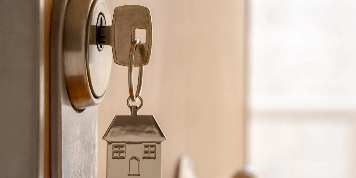 close up of key and house keychain ​​in high security door lock home insurance concept copy space