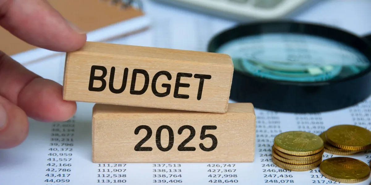 hand holding wooden block with text - budget 2025 with financial data background budgeting concept