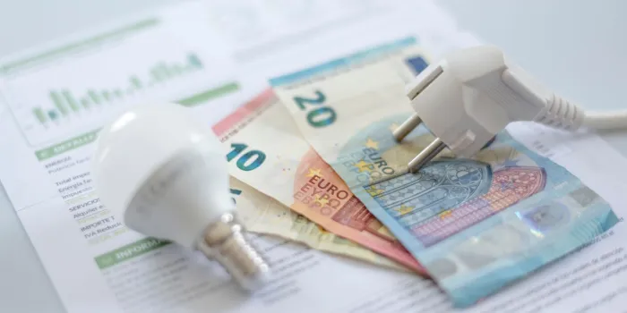a white electric cap, a light bulb and euro banknotes on an electric bill increase in the cost of electricity for residential customers and business users payment of electricity bills increasing the concept of electricity prices