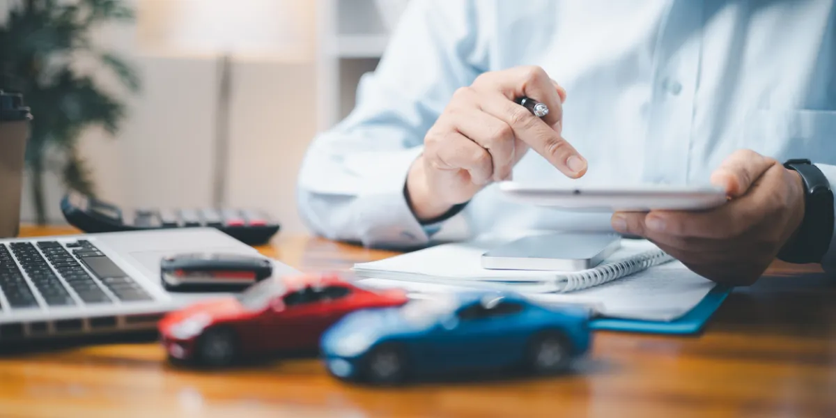 Homme avec paperasse face à petites voitures