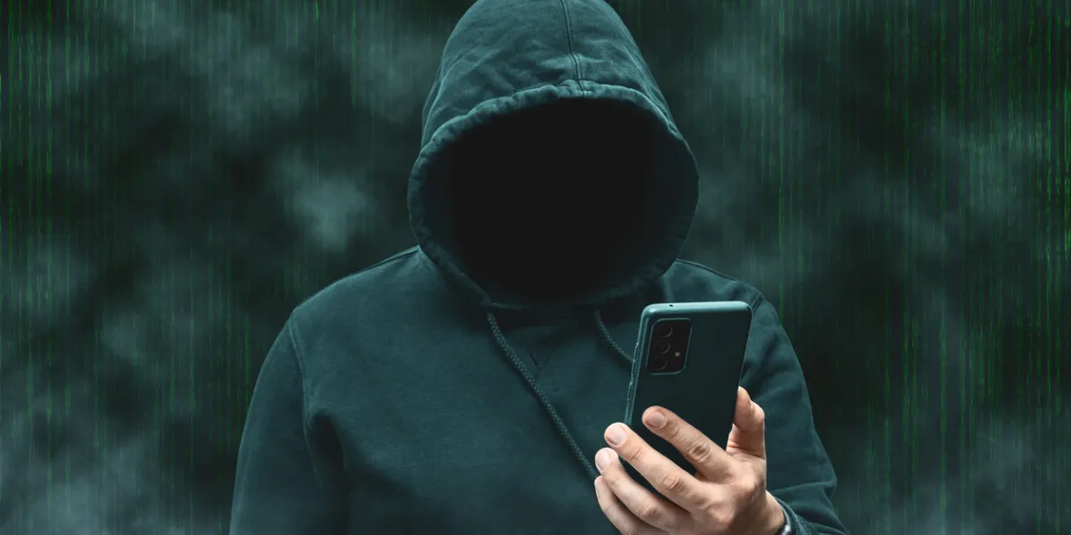 Mystérieux pirate anonyme sans visage à capuche tenant un smartphone