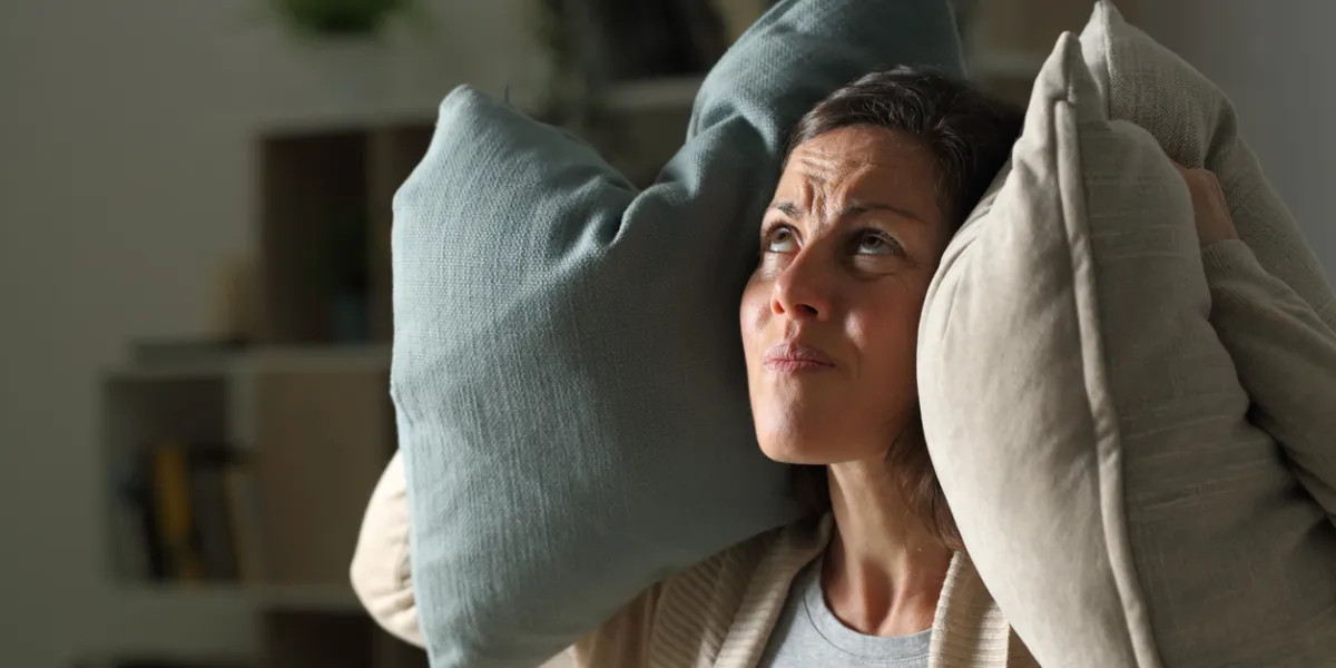 Femme adulte ennuyée souffrant le bruit de voisin la nuit à la maison