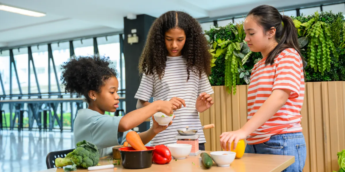 Des enfants préparant des aliments sains avec des légumes dans une activité éducative en classe sur la nutrition et la santé
