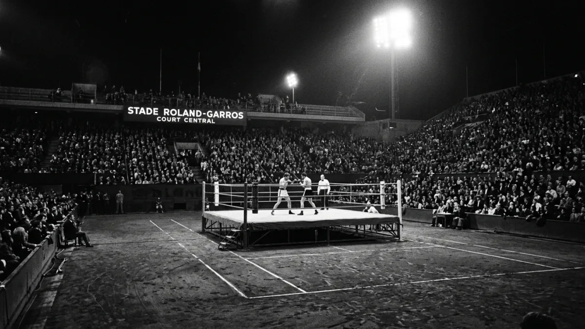 Ring de boxe éclairé sur la terre battue de Roland-Garros en 1973.