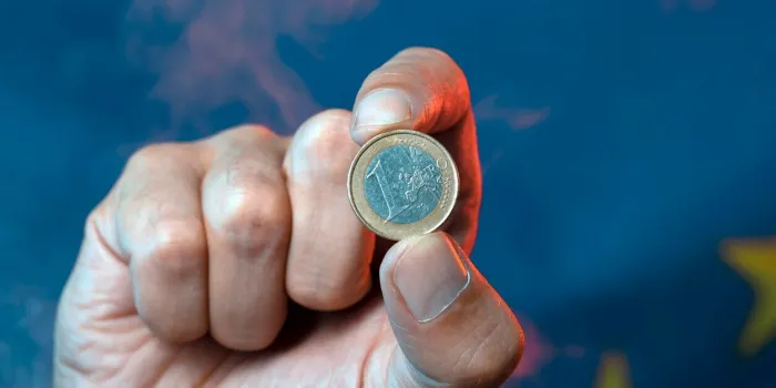 one euro coin in hand against the background of the european union flag