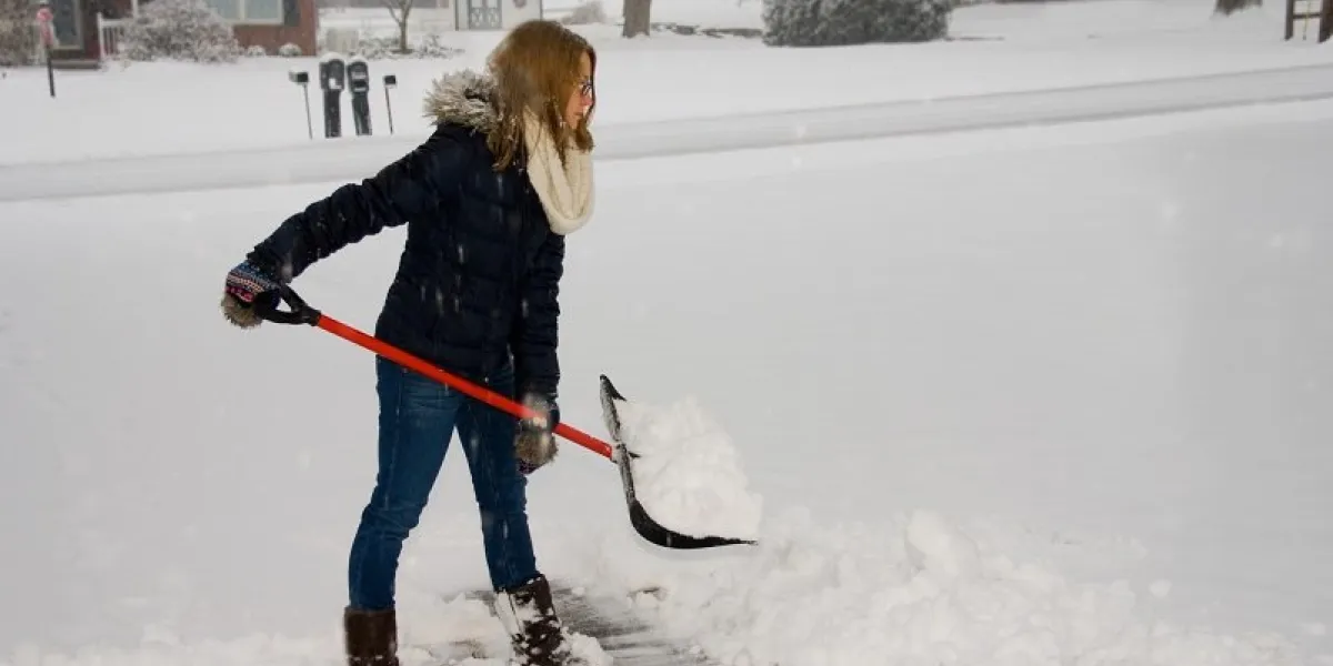 a young woman ready to throw a shovel full of snow