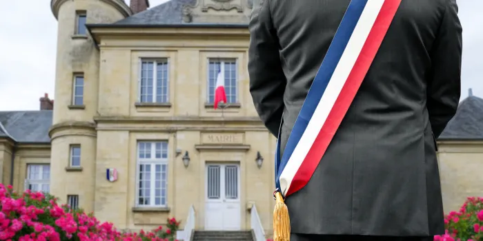 a mayor with his tricolor scarf in front of his town hall