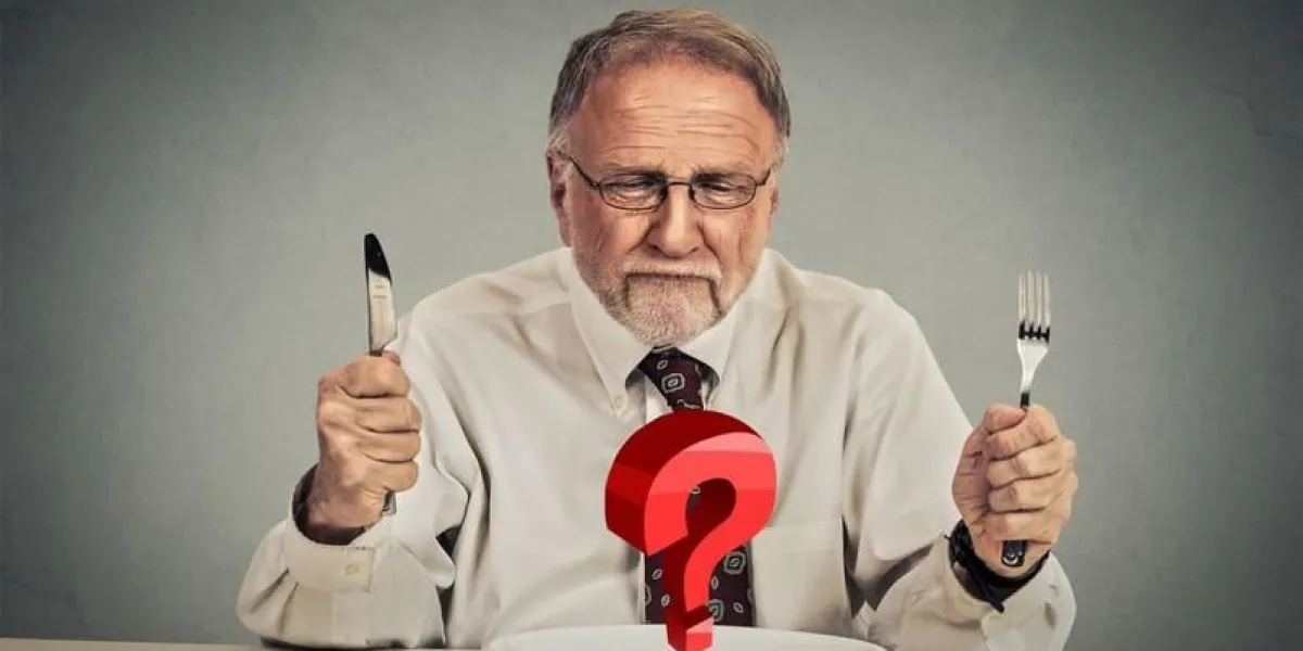 elderly man with silverware looking at plate with question mark having problems with diet