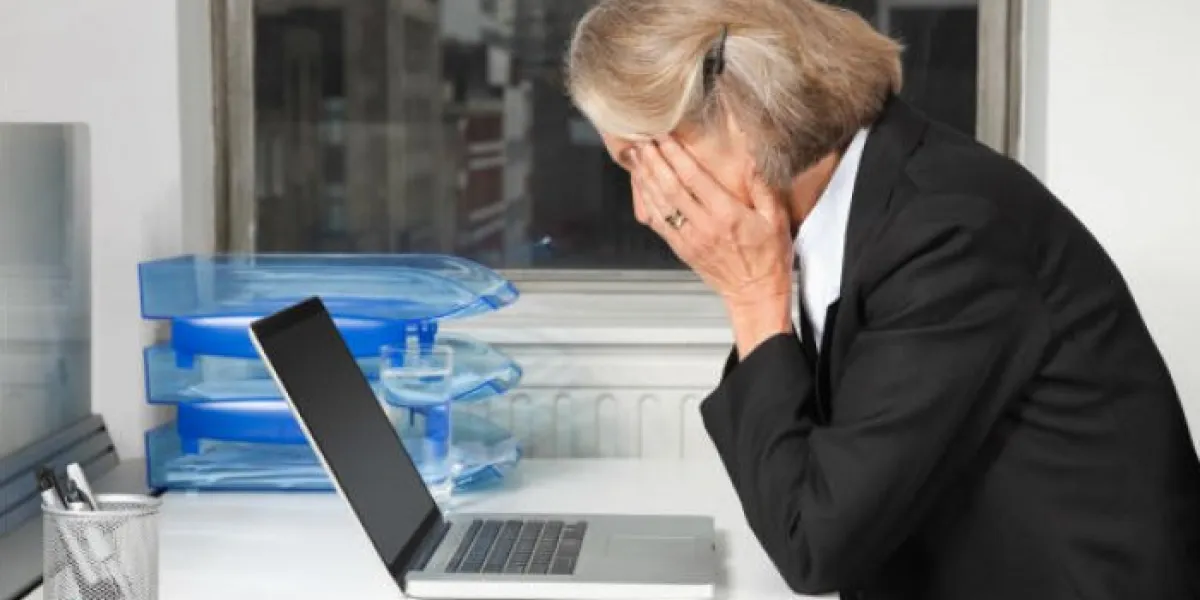 vue de côté de femme d'affaires senior fatigué en face de l'ordinateur portable au bureau au bureau