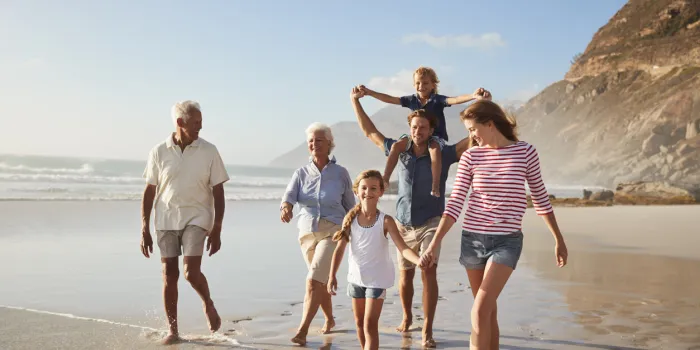 multi generation family on vacation walking along beach together
