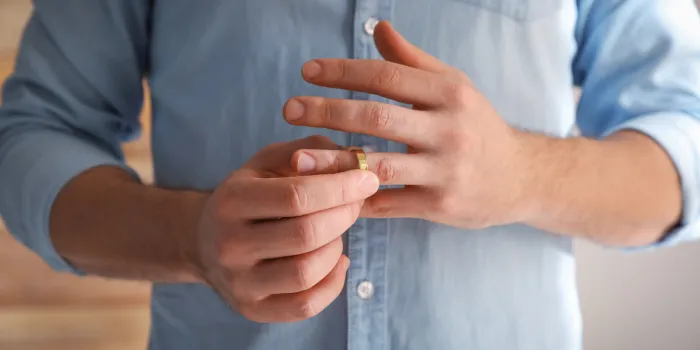 man taking off wedding ring on blurred background, closeup divorce concept