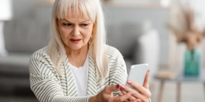 suspicious sms worried mature woman looking at smartphone screen, received bad news, got fishy scam message, doubtful confused lady holding gadget with concerned face expression, free copy space