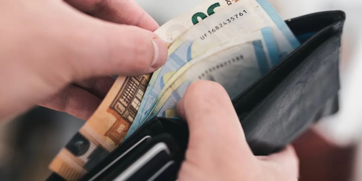 close-up view of hands taking money out of a wallet, spending cash concept