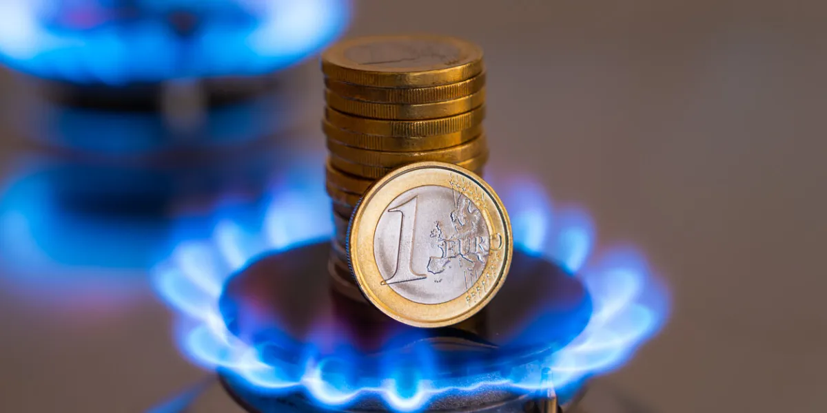 gas stove lit, with stacks of coins above it increase in gas costs and tariffs