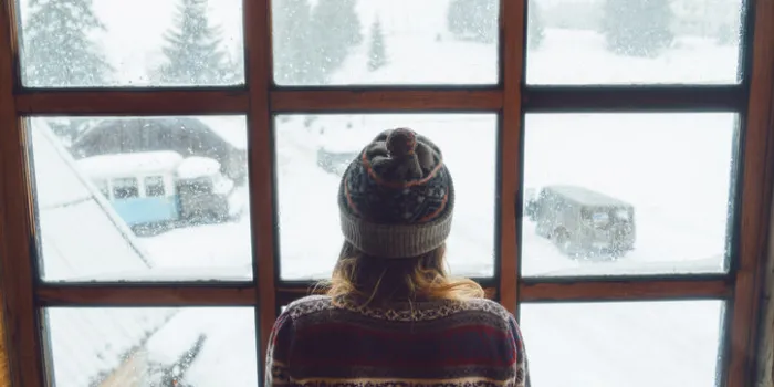 young caucasian woman looking in the window in winter
