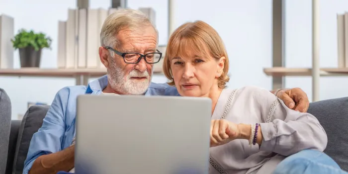 mature woman and senior man using laptop in living room, portrait of worried senior couple checking their bills and work on netbook read document information at home