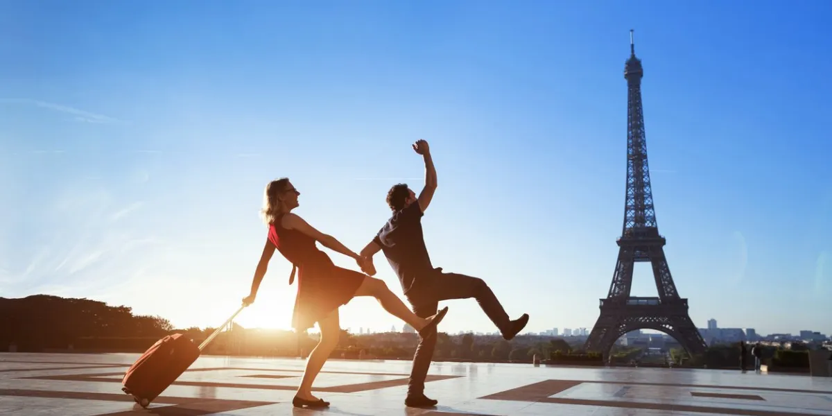 couple of crazy tourists on holidays in paris, man and woman having fun near eiffel tower, travel with luggage, tourism