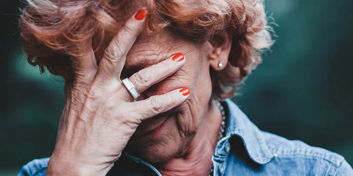 older women worrying with her hands over her face