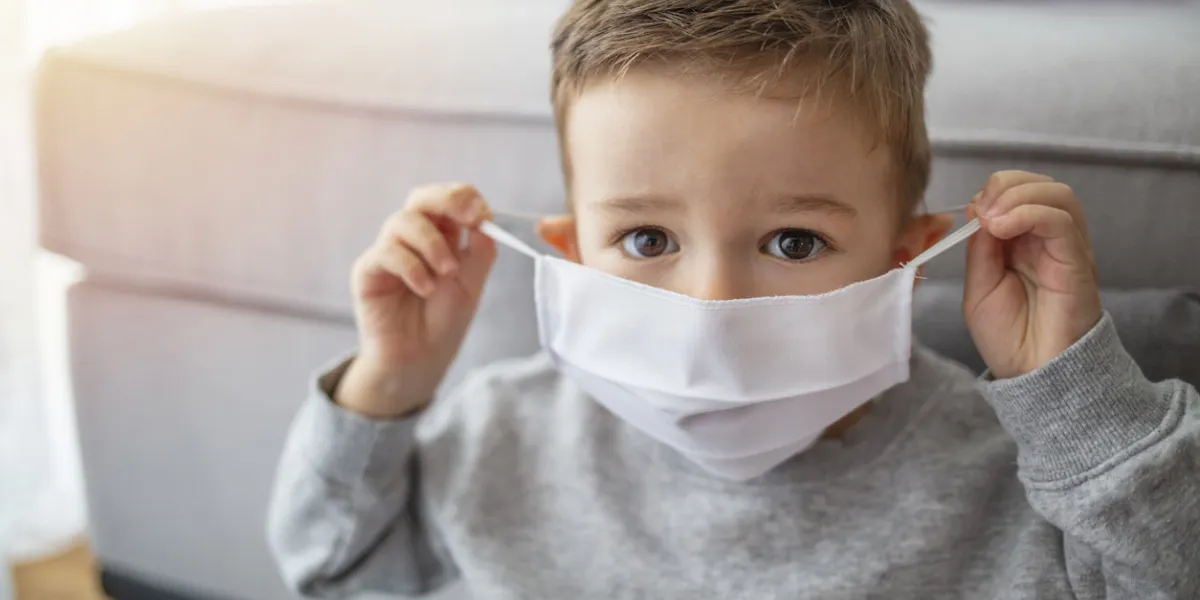 young child wearing a respiratory mask as a prevention against the coronavirus covid-19 little boy wearing anti virus mask staying at home protection against flu and virus infection