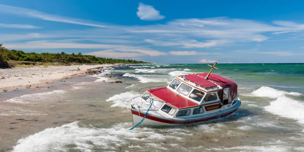 stranded red boat on beach after storm
