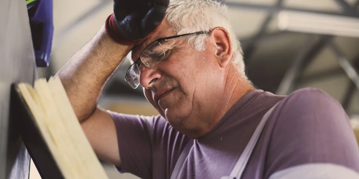 senior man in workshop worried man reading his planner