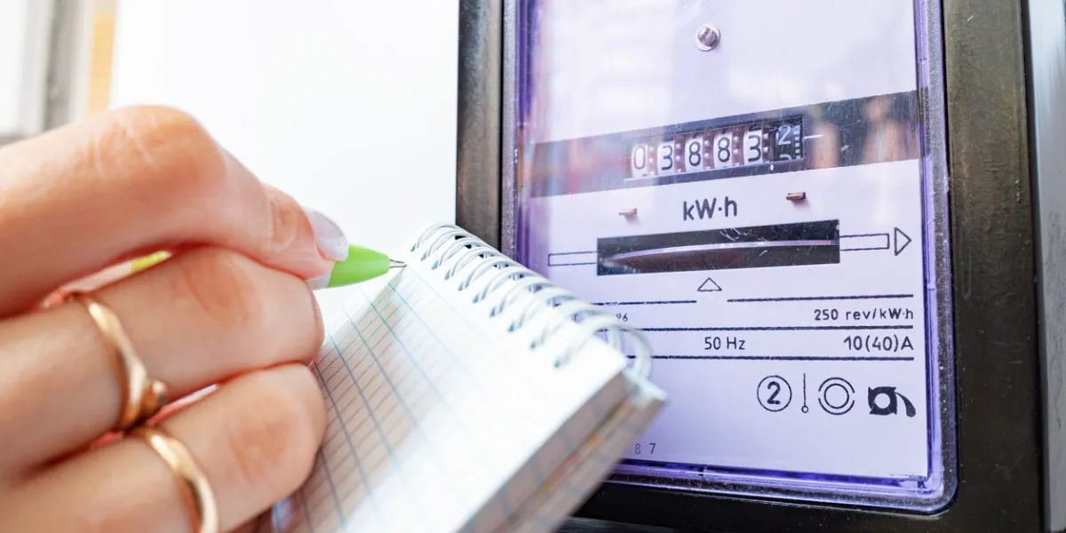 woman's hands with pen and notepad writes the electricity meter readings at home
