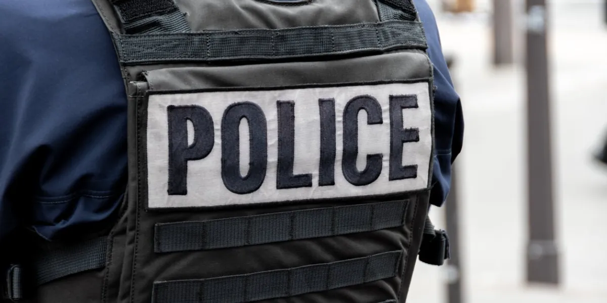 close-up 'police' marking written on the back of a bulletproof vest worn by a french police officer on a street in paris, france concepts of law enforcement, crime, delinquency and criminal affairs