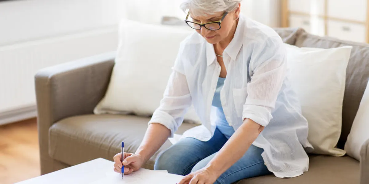 business, savings, annuity insurance, age and people concept - senior woman with papers or bills and calculator writing at home