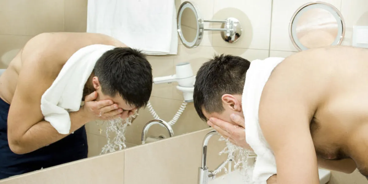 homme séduisant, laver le visage dans la salle de bain hôtel