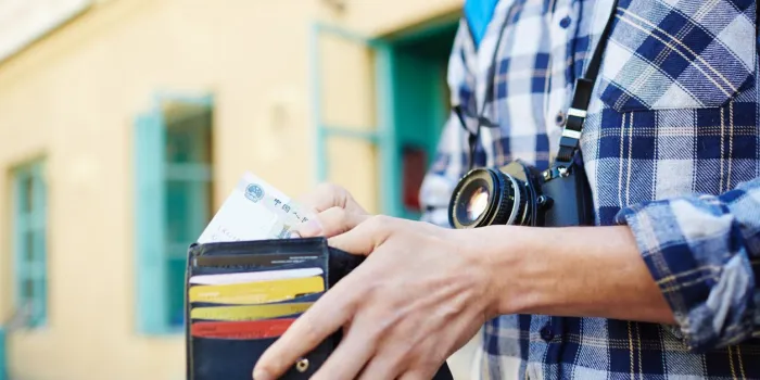 closeup image of young tourist putting money in wallet, saving money for vacation trips