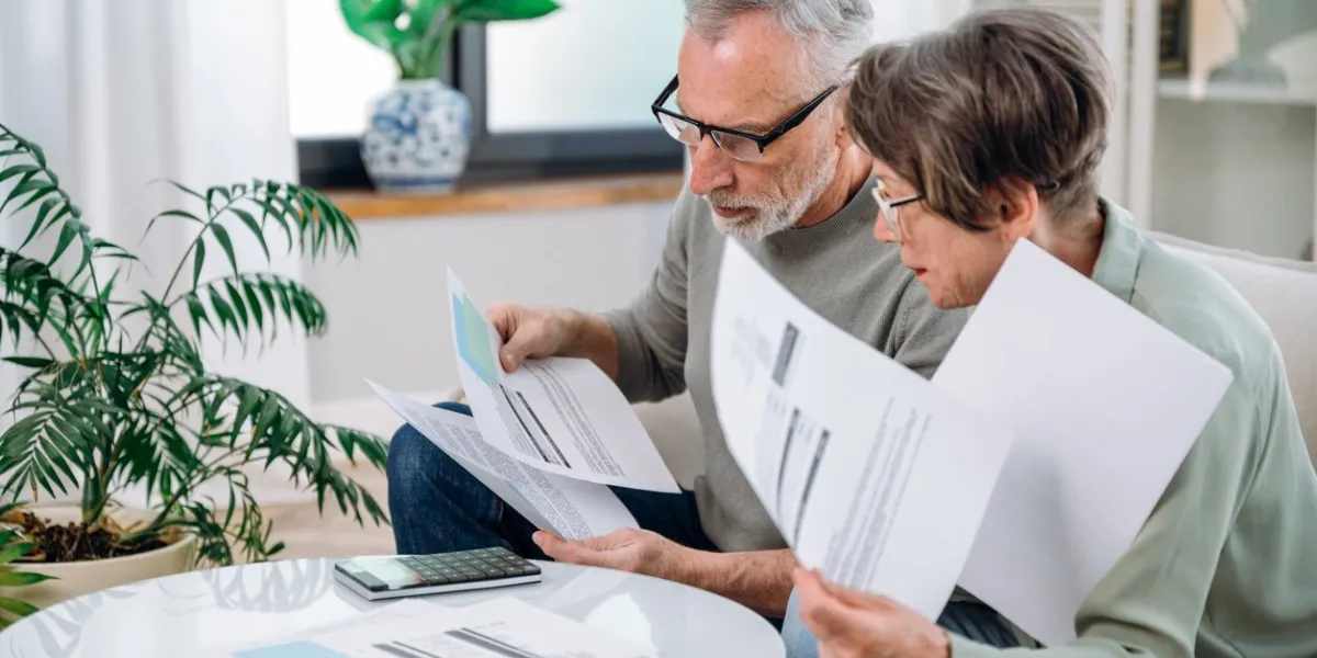 elderly couple checking documents with tax and internal bills, making payments and discussing budget family calculating funds for purchase new home or car
