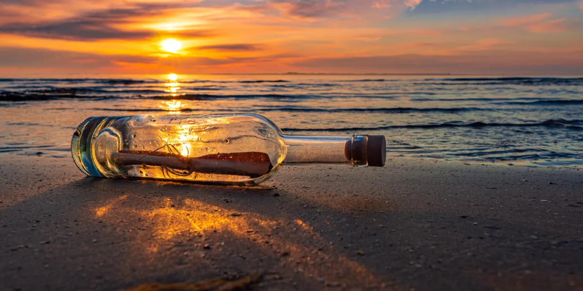 message in a corked bottle on beach, asking for help
