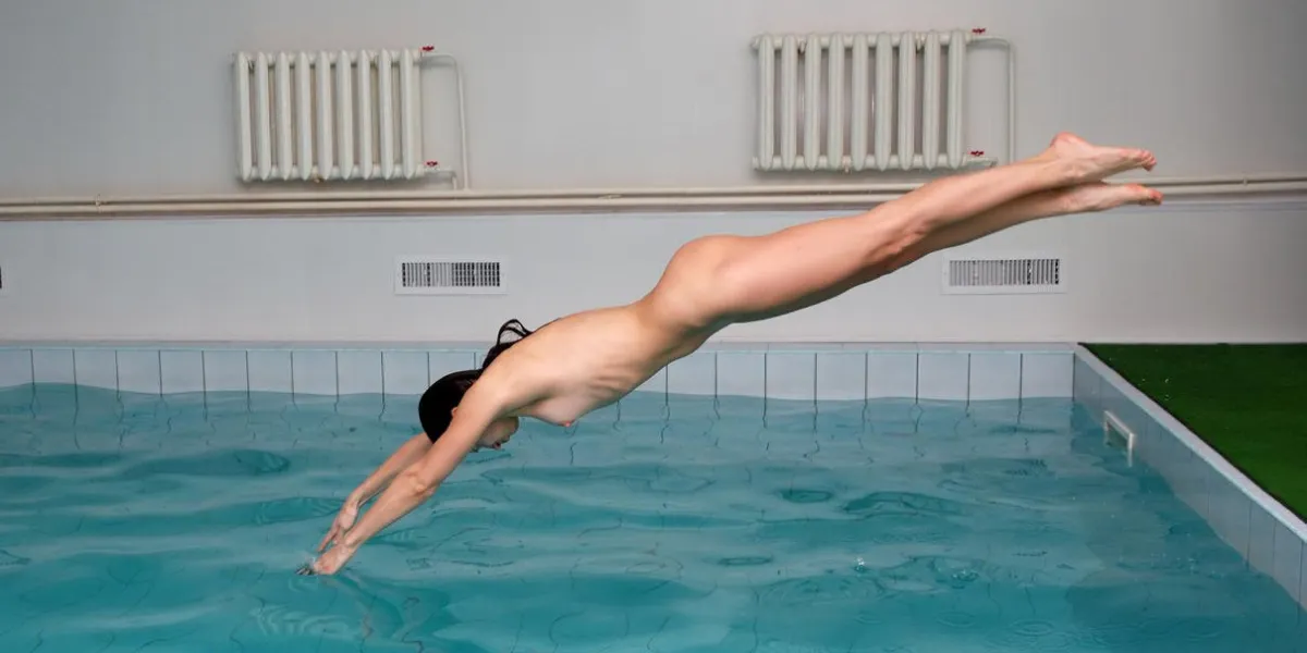 femme saute dans l'eau aigue-marine de la piscine, nue et tendue beau corps