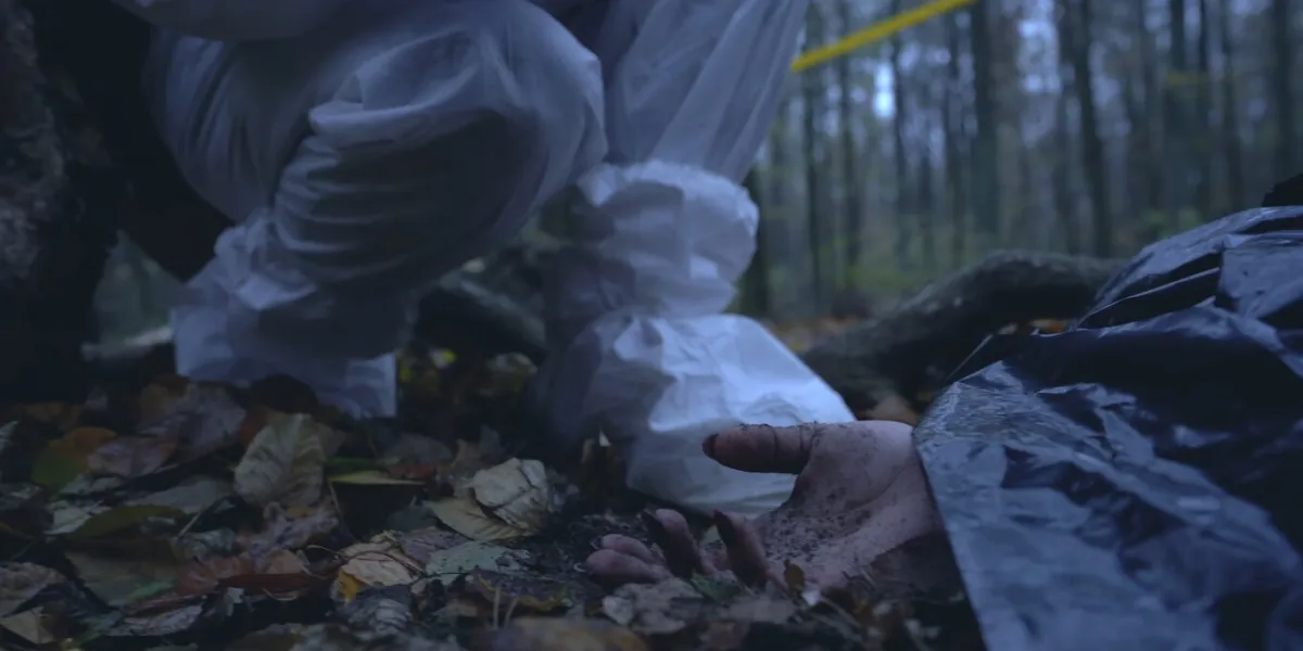 forensic investigator takes a photo of the hand of a deceased person discovered in the forest, documenting the crime