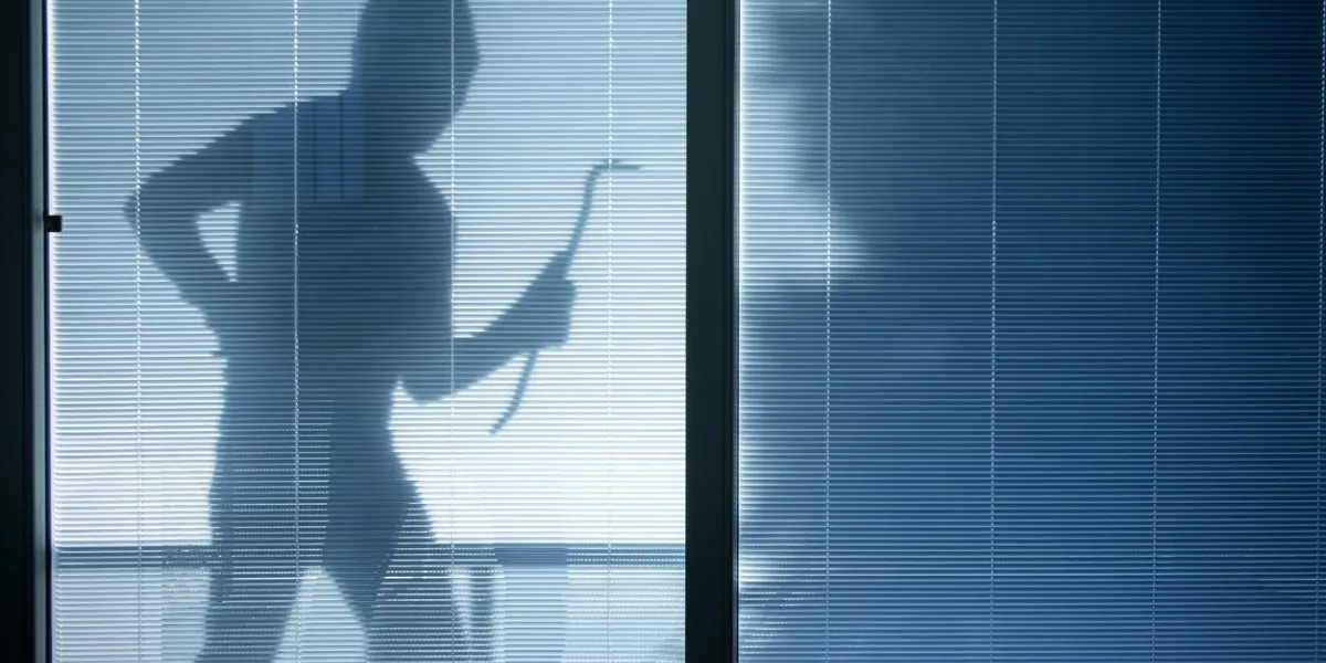 burglar wearing a balaclava looking through the house window