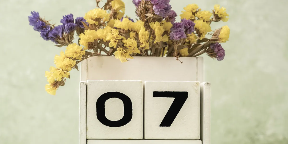 cube calendar for april decorated with flowers against green background with copy space