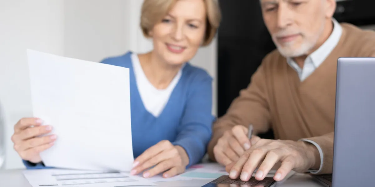 elderly married calculated expenses for utility bills, checking family accounting, payment of taxes and mortgage loan senior couple pension savings, selective focus on calculator