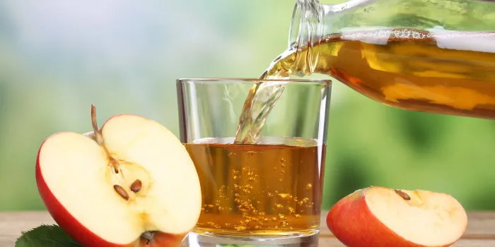 apple juice pouring from red apples fruits in summer into a glass