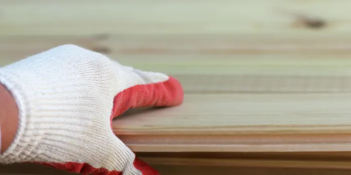 working hand in protective gloves holding a wooden board