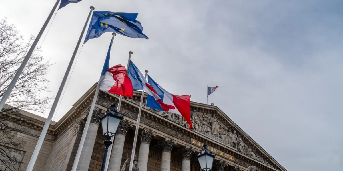french and european union flags in the wind in front of national assembly in paris - aka assemblee nationale or palais bourbon