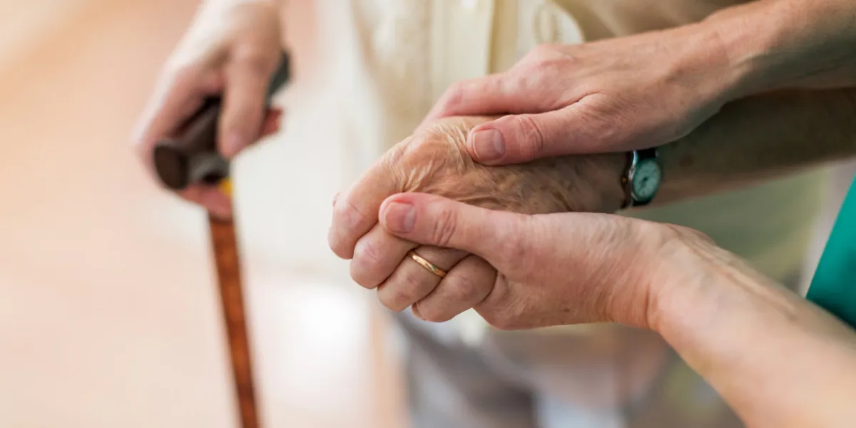 nurse consoling her elderly patient by holding her hands