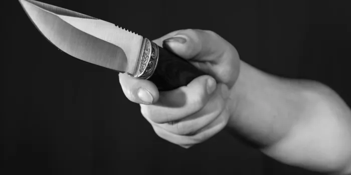 man's hand holding knife close up view on black background