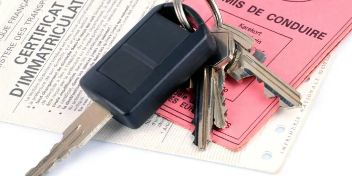 car key placed on a driver's license and a registration certificate on a white background