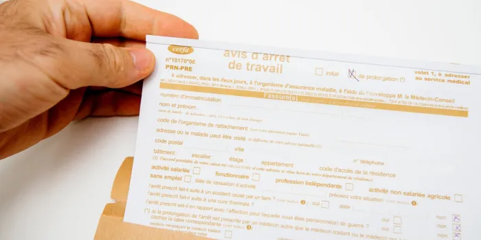 paris, france - jun 19, 2019  patient male man holding above white executive table the avis d'arret de travail sick leave issued by treating doctor medical justification