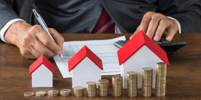 section médiane de l'homme d'affaires, calcul de la taxe par des maisons de différentes tailles et des piles de pièces de monnaie sur la table