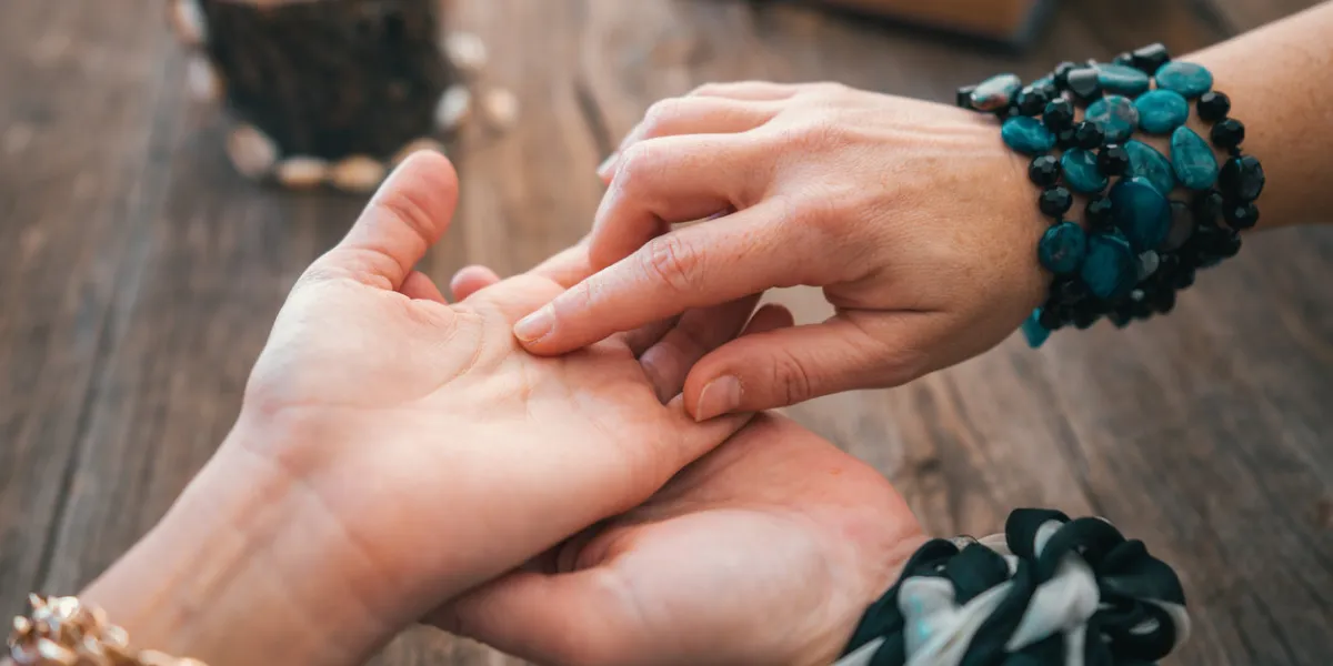close up of fortune teller point her finger to woman's palm line and read her fortune palmistry cpncept