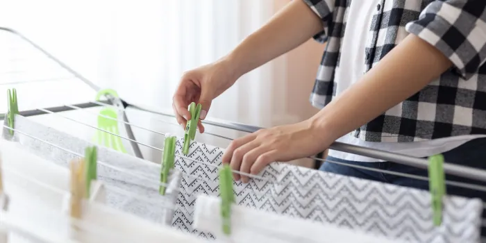detail of female hands hanging the washing out to dry on a drying rack focus on the clothespin and the hand holding it