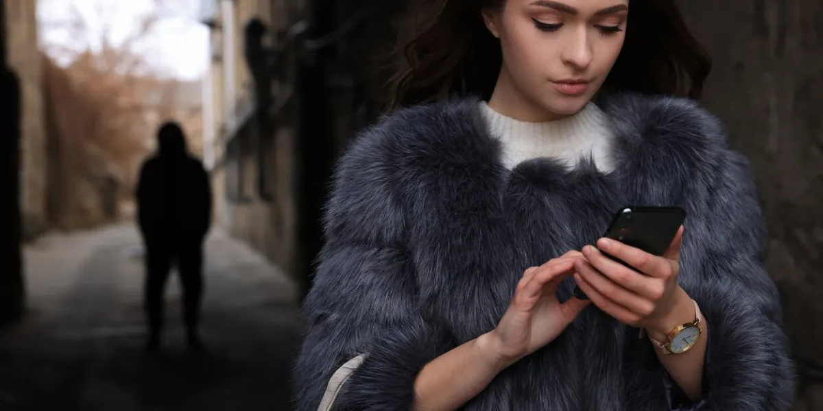 man stalking young woman with phone in alley